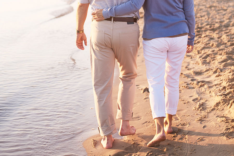 Dos personas mayores caminan juntas por la playa