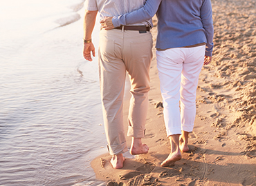 Dos personas mayores caminan juntos por la playa